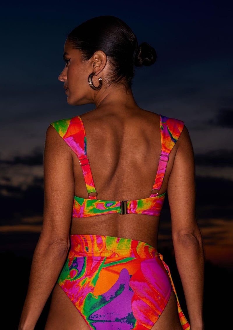 A female model faces backwards. She wears Dancing Leopard tropical print bikini bottoms with a matching bikini top.