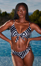 Female model faces forward in front of a pool. She wears a Dancing Leopard monochrome bikini top with matching bikini bottoms.