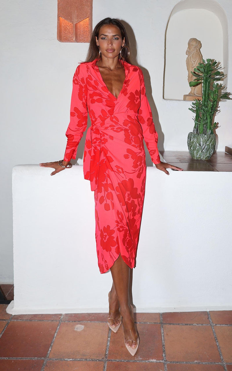 A female model faces forward. She wears a Dancing Leopard midi length, long sleeved dress. It is pink with red flower print.