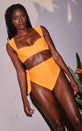 A female model faces forward. She wears a Dancing Leopard orange bikini top with matching bikini bottoms.