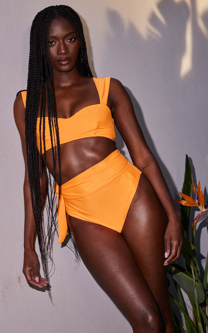 A female model faces forward. She wears Dancing Leopard orange bikini bottoms with a matching bikini top.