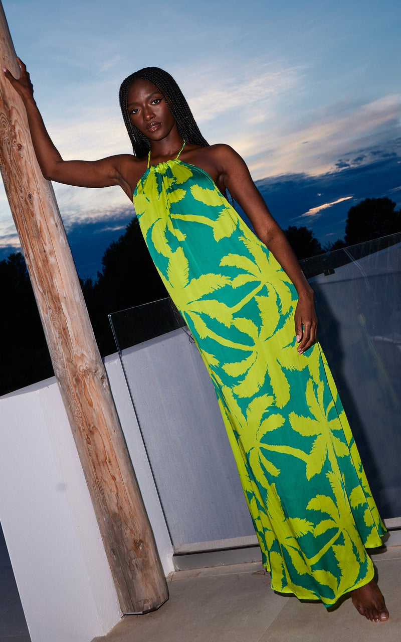 A female model faces forward. She wears a Dancing Leopard green, topical print maxi dress.