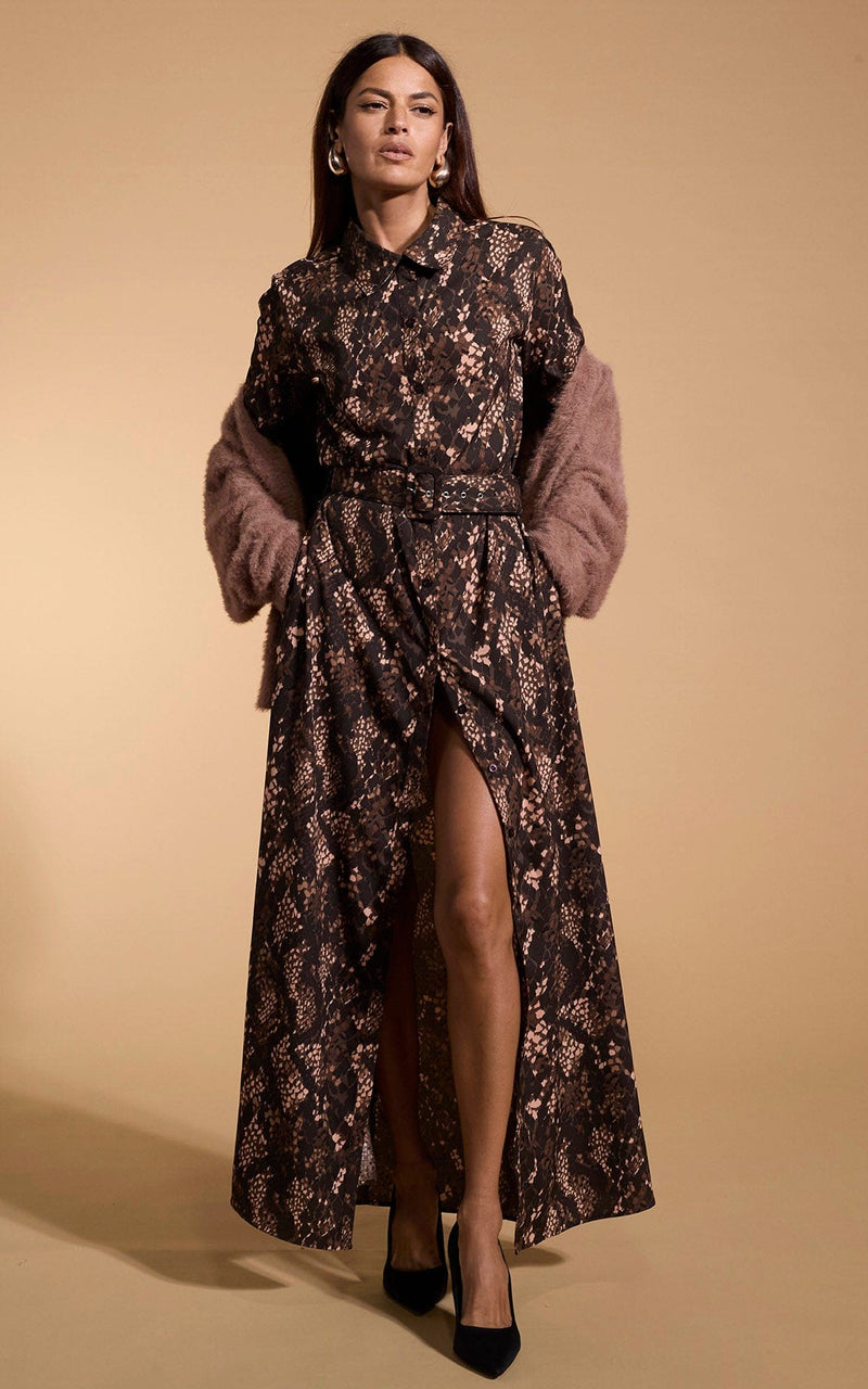 A female model faces forwards. She wears a Dancing Leopard maxi shirt dress, in brown with a snake skin print.