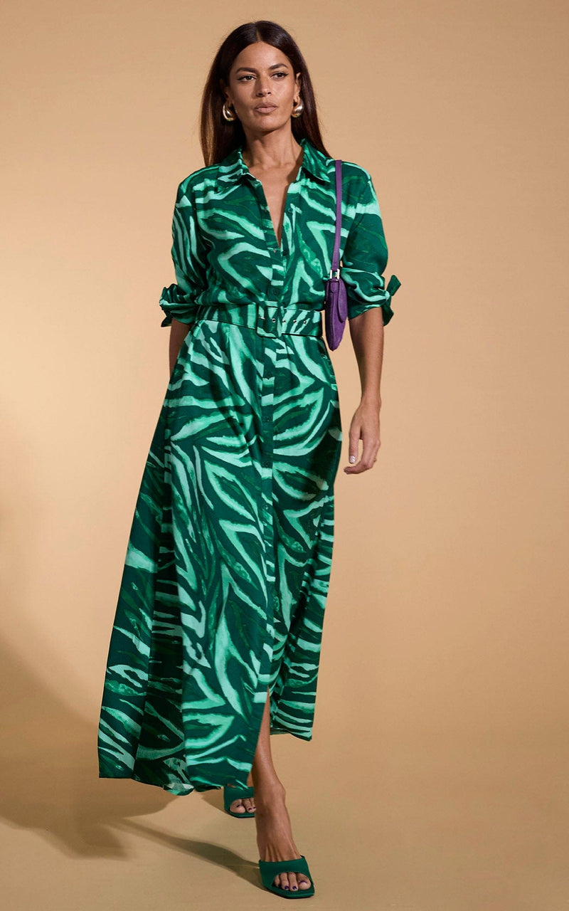 A female model faces forwards. She wears a Dancing Leopard maxi shirt dress, in green zebra print.