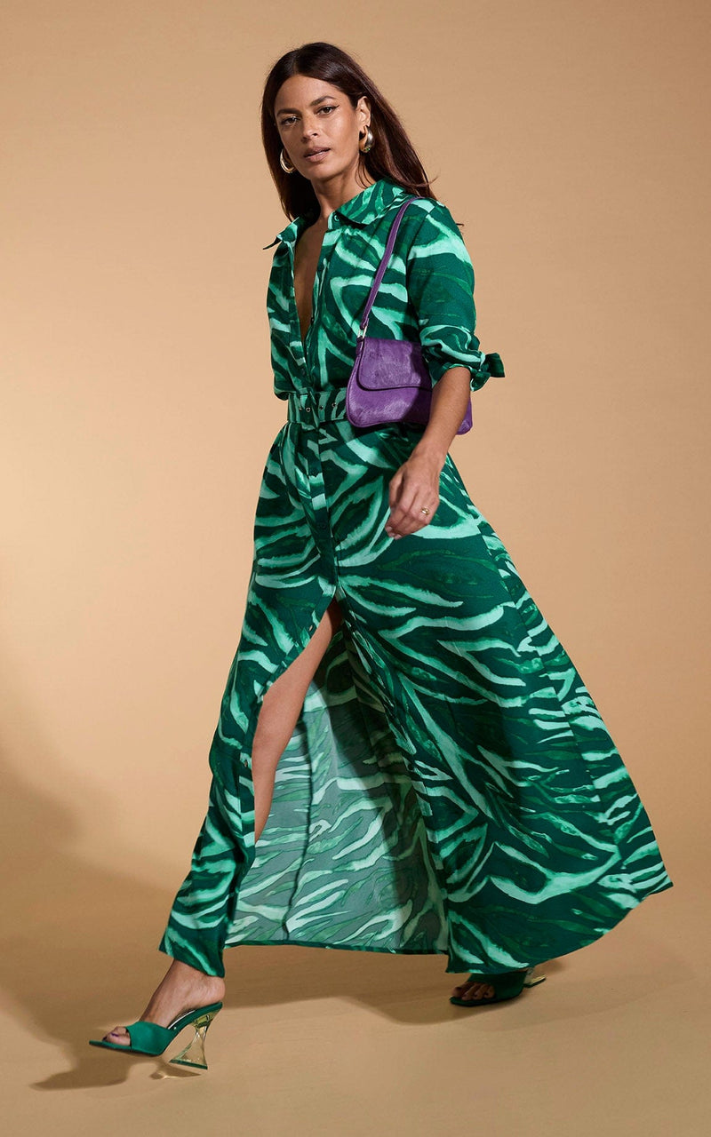 A female model faces forwards. She wears a Dancing Leopard maxi shirt dress, in green zebra print.