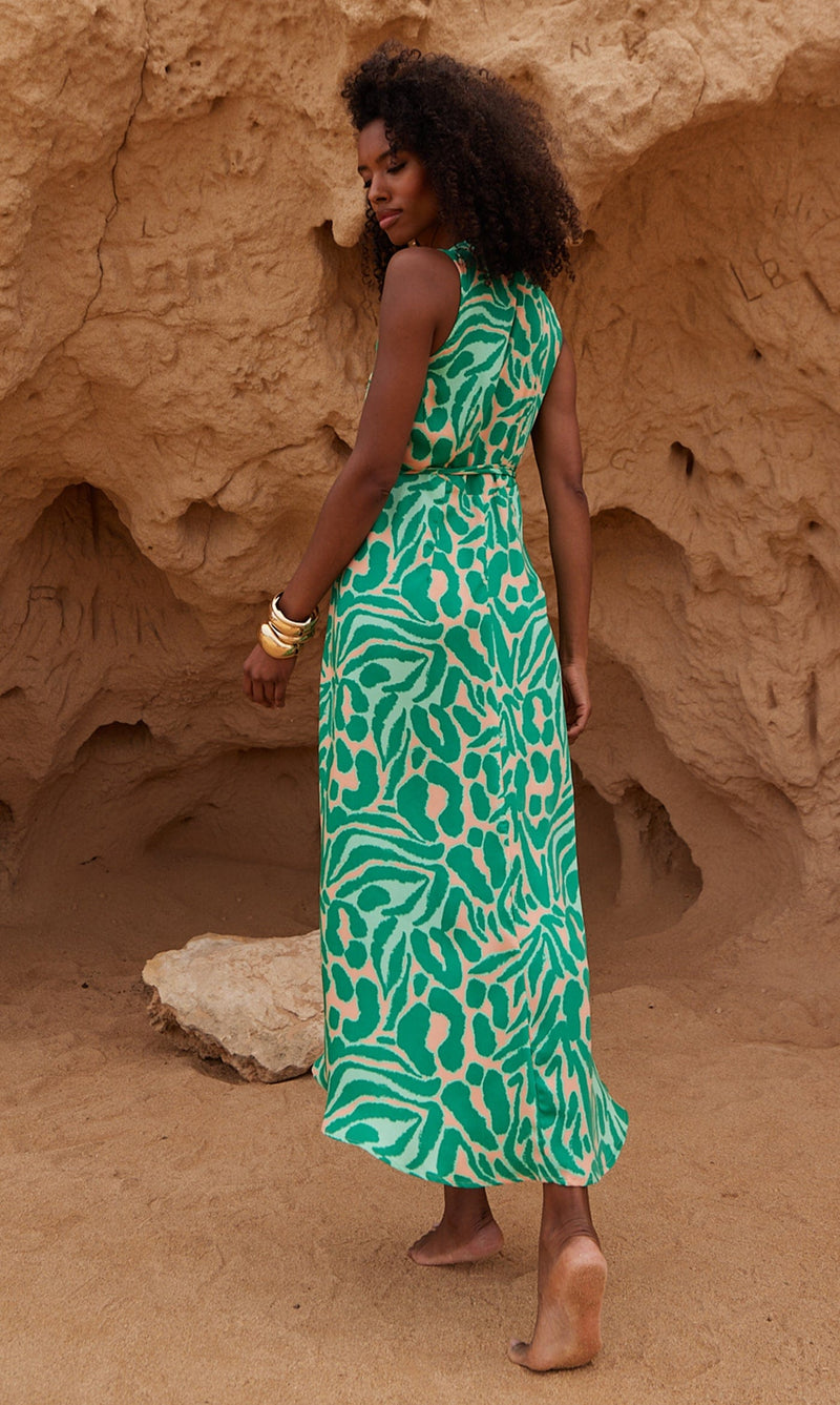 A female model faces backwards. She wears a Dancing Leopard green and peach, zebra print wrap dress.