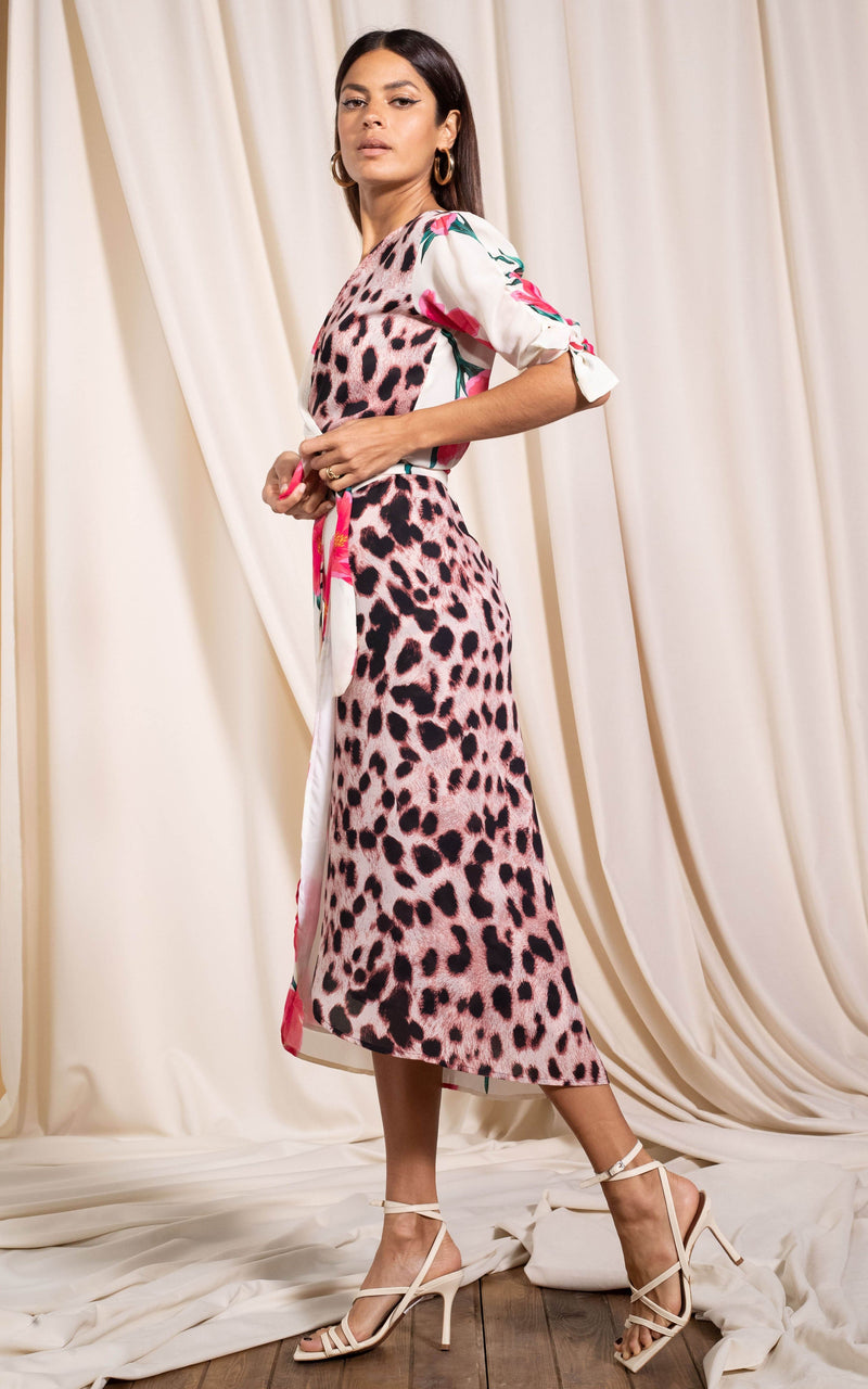 Dancing Leopard model standing sideways wearing Olivera midi dress in cream base tulip mix holding onto waist tie