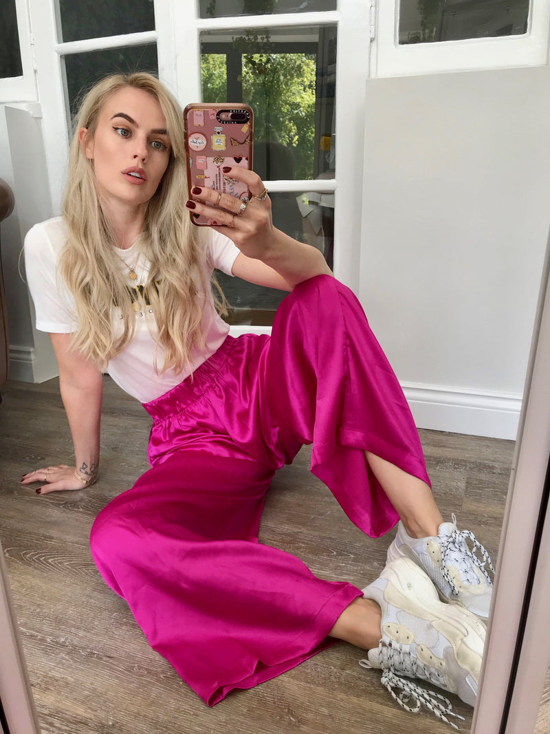 Front-facing model sitting down wearing Chinchilla Trousers in magenta pink by Dancing Leopard